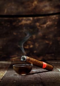 smoking cigar propped up on ash tray